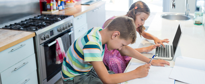 Brother and sister working on their homeschool work in the kitchen